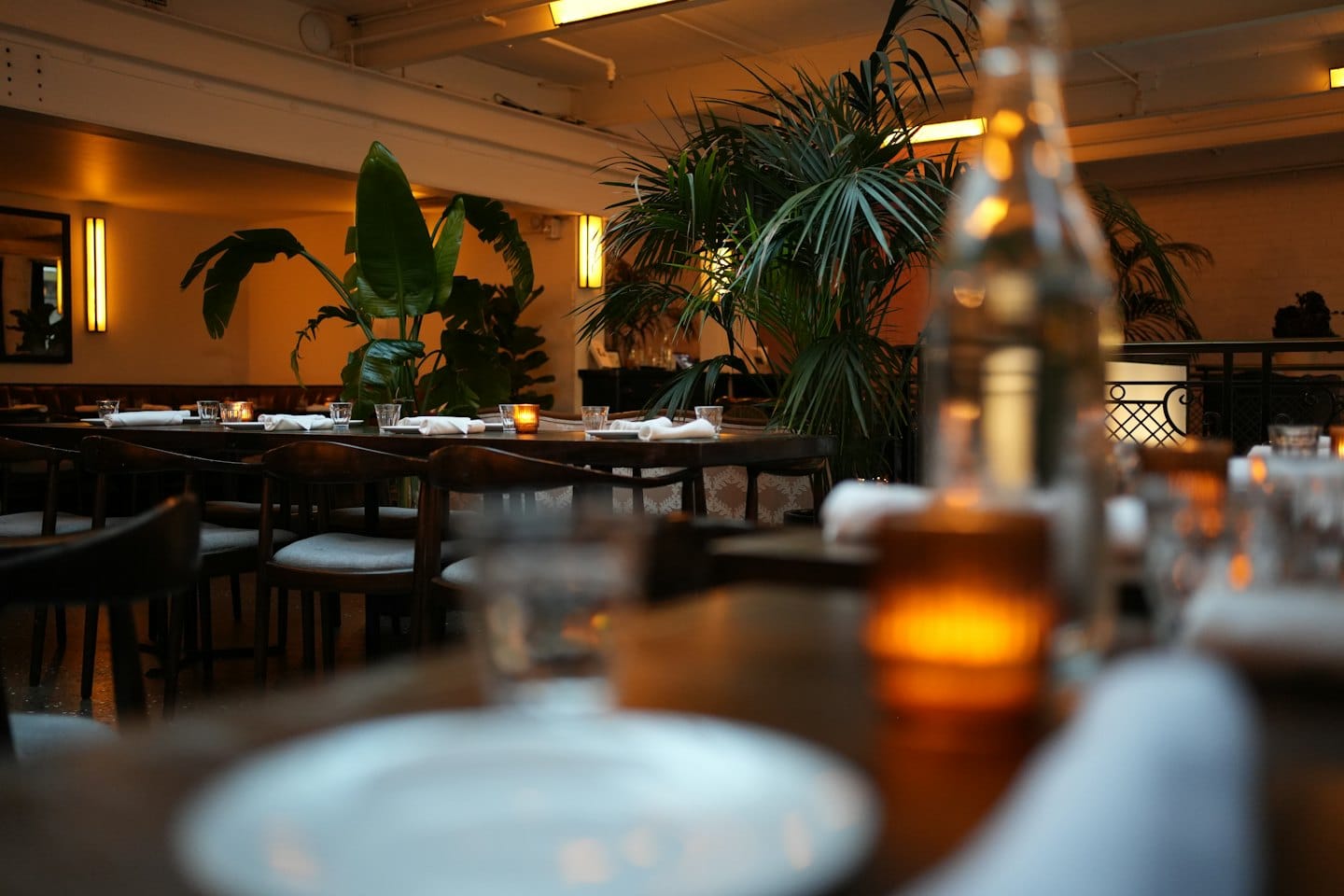 Tavoli di legno apparecchiati con candele in un ristorante accogliente.