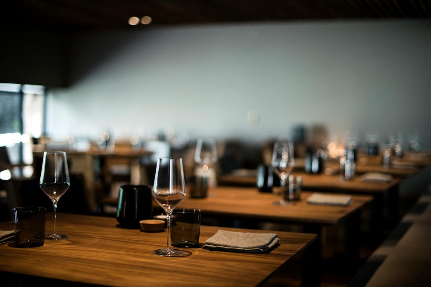 Tavoli di legno elegantemente apparecchiati per un pasto in un ristorante.