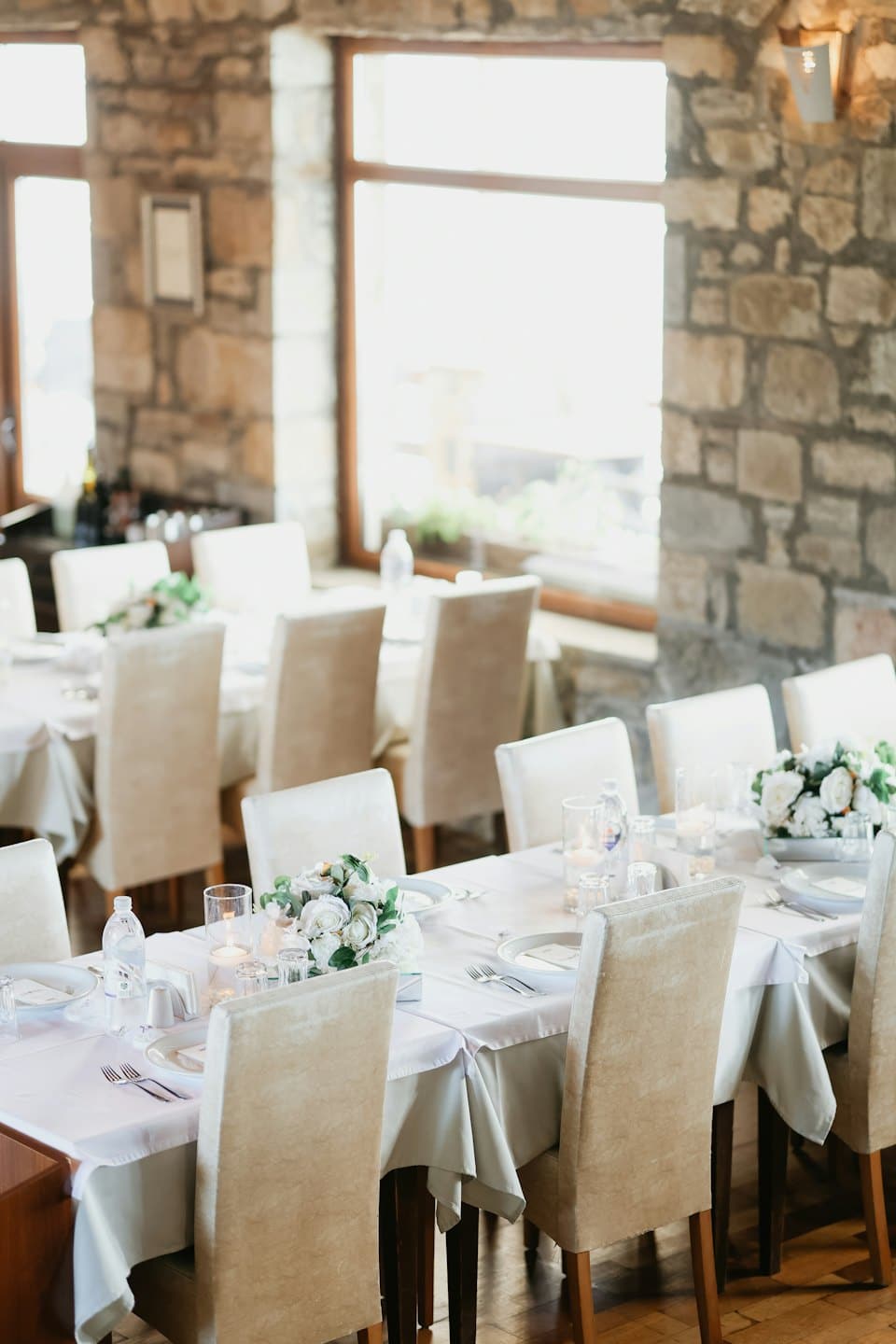 Eleganti tavoli da pranzo apparecchiati con tovaglie bianche e candele.