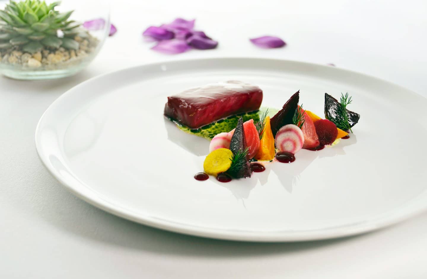 Piatto gourmet di carne rossa con verdure colorate su un piatto bianco.