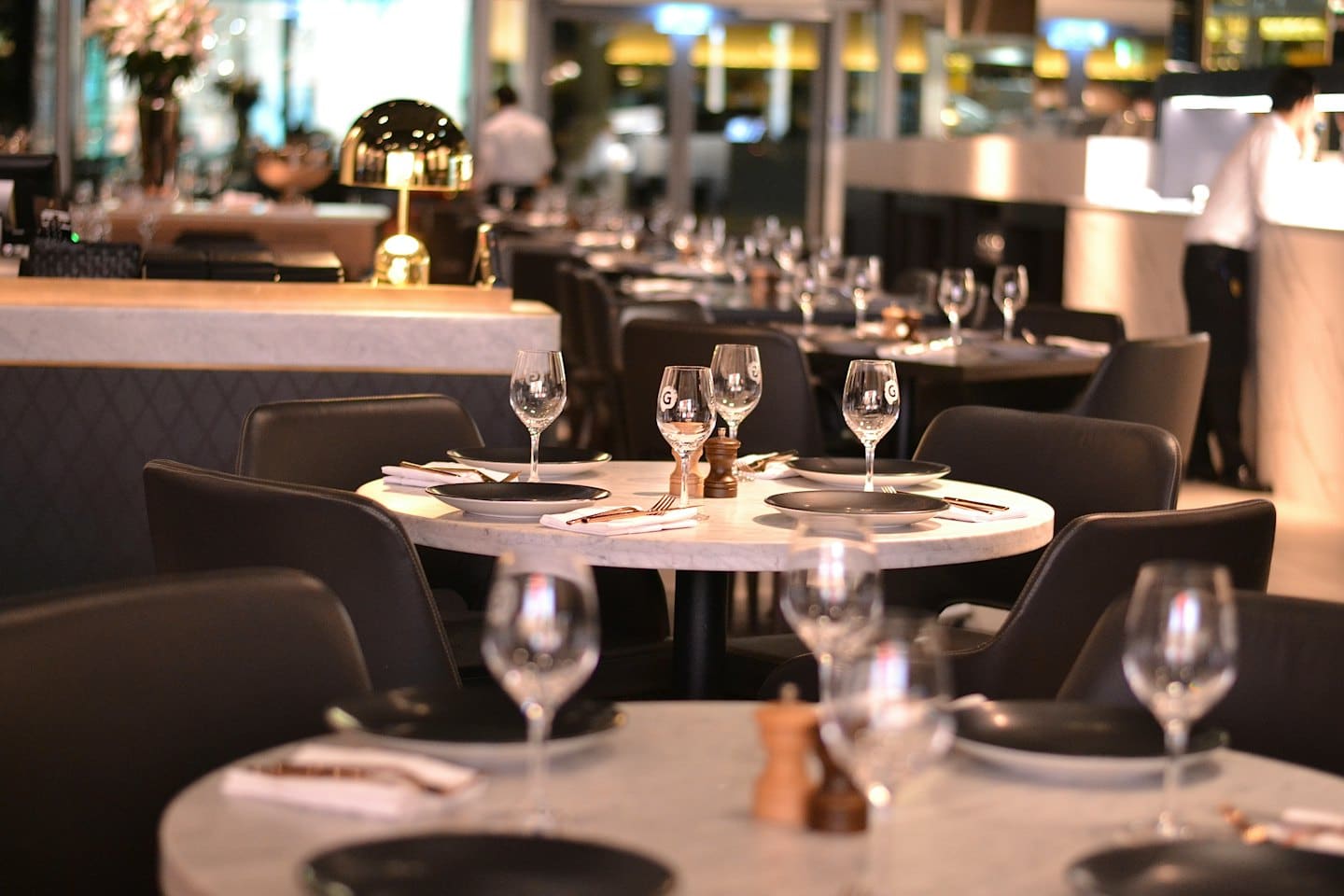 Sala da pranzo elegante di un ristorante con tavoli in marmo e sedie in pelle.