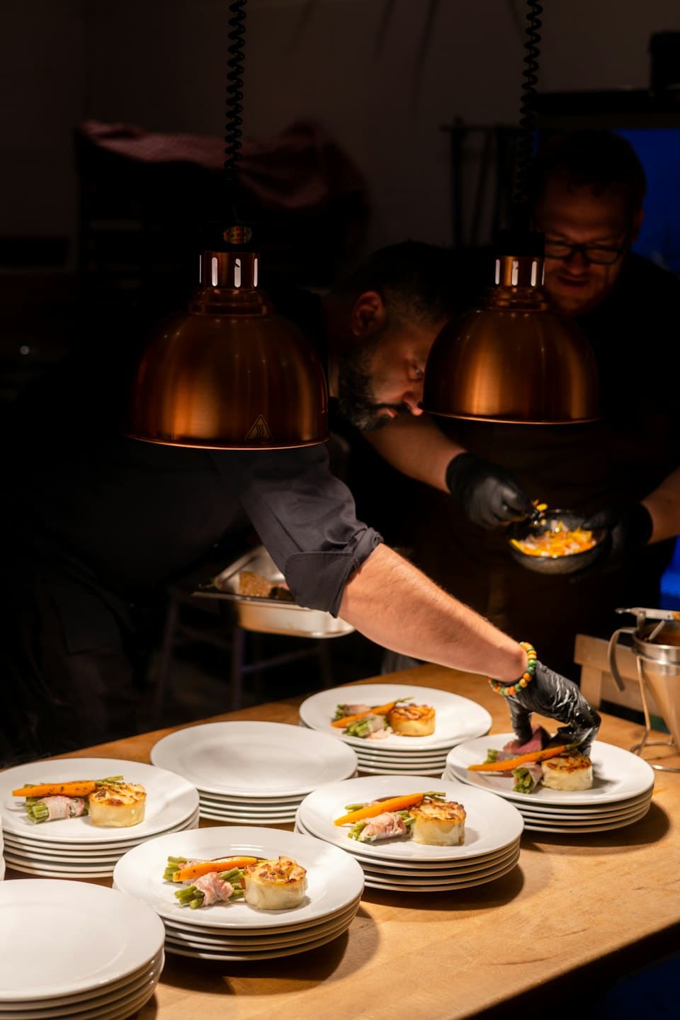 Due chef impiattano con cura piatti gourmet in una cucina professionale.